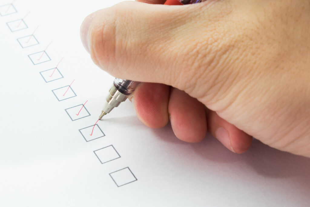 Hand hält Stift und checkt Boxen